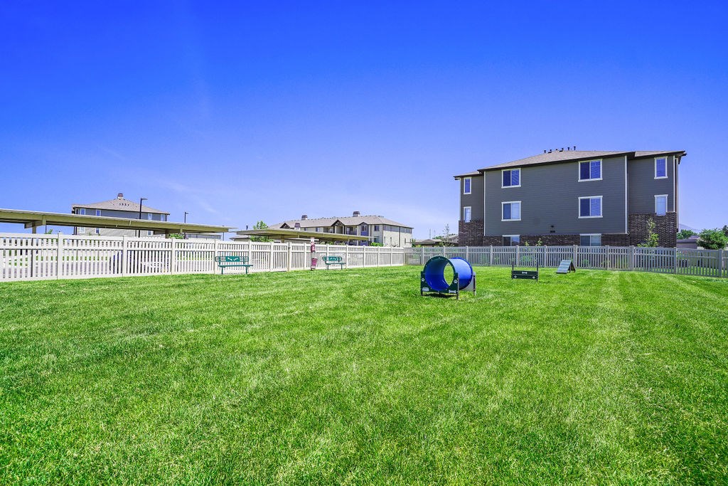 A grassy field with a blue tube and a white fence.