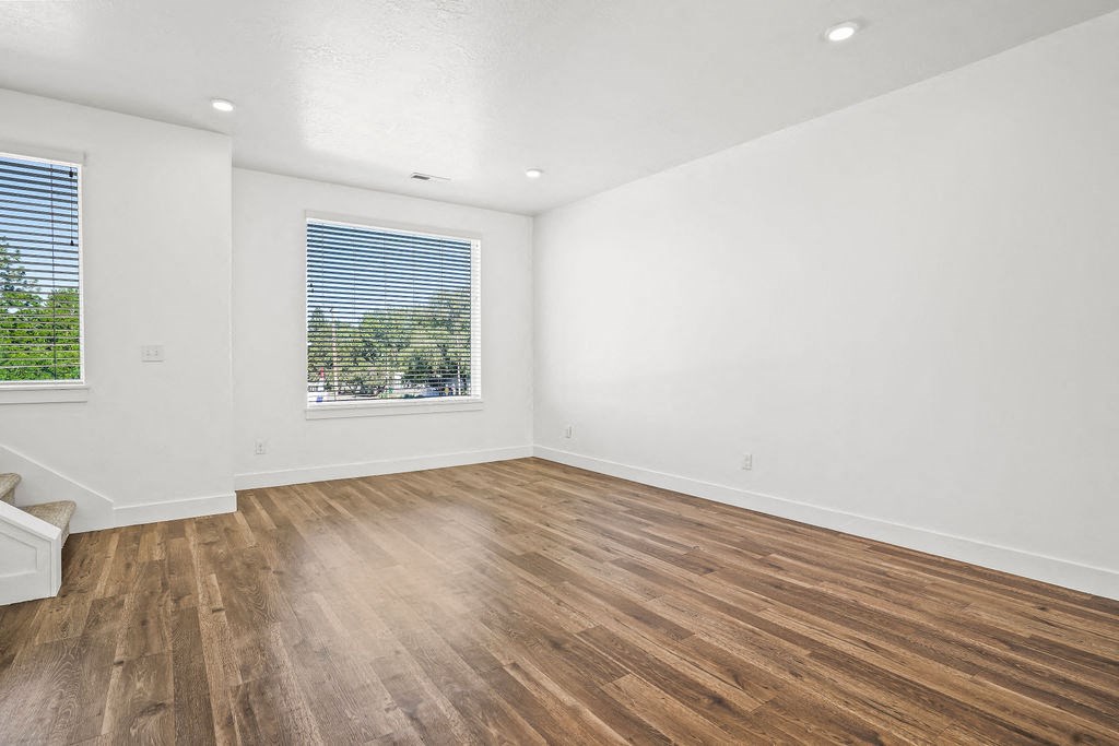 an empty living room with wood floors and a window  at Aero Luxury Townhomes in Layton, Utah
