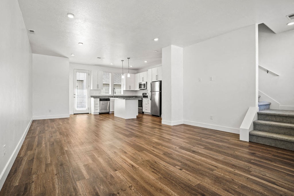 an empty living room with a kitchen and stairs  at Aero Luxury Townhomes in Layton, Utah