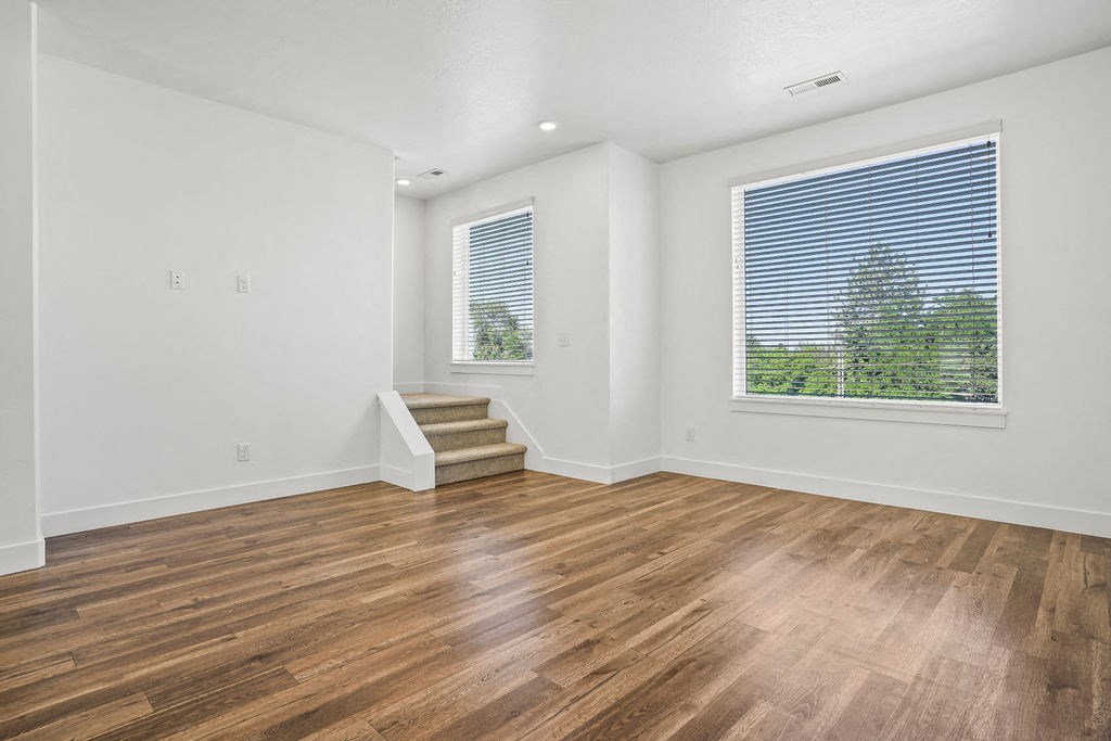 an empty living room with wood floors and a large window  at Aero Luxury Townhomes in Layton, Utah