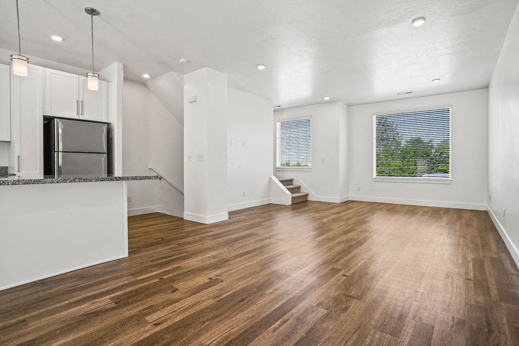 an empty living room and kitchen with wood floors and a refrigerator  at Aero Luxury Townhomes in Layton, Utah