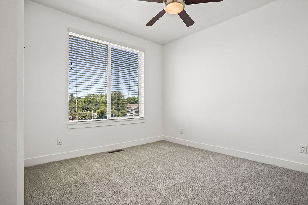 an empty living room with a large window and a ceiling fan  at Aero Luxury Townhomes in Layton, Utah