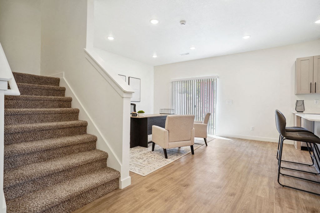 a living room with a staircase and a dining room with chairs
