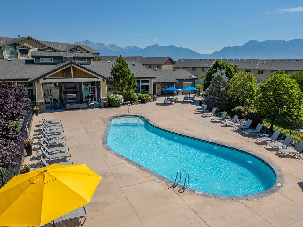 our resort style swimming pool with lounge chairs and a yellow umbrella at Aldara Apartments in Saratoga Springs, Utah