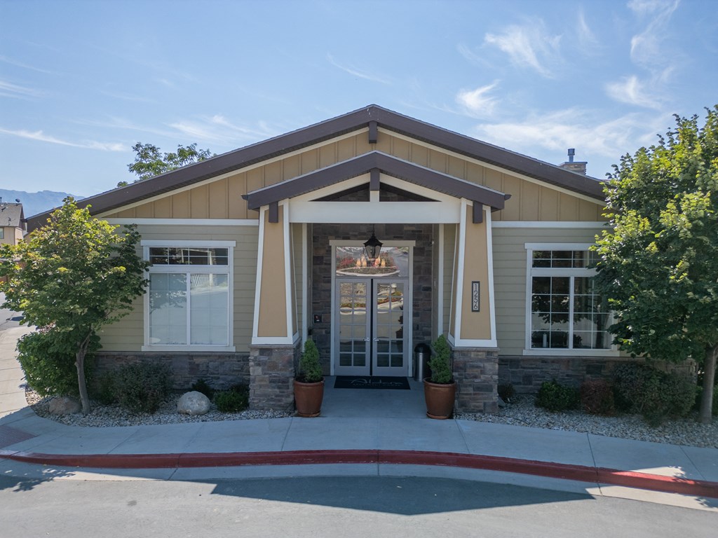 the front entrance of a tan house with a driveway and trees at Aldara Apartments in Saratoga Springs, Utah