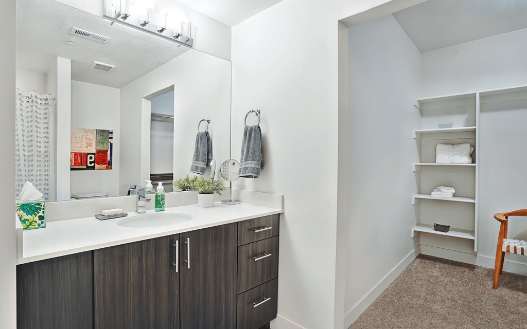 A bathroom with a sink, mirror, and towel rack.