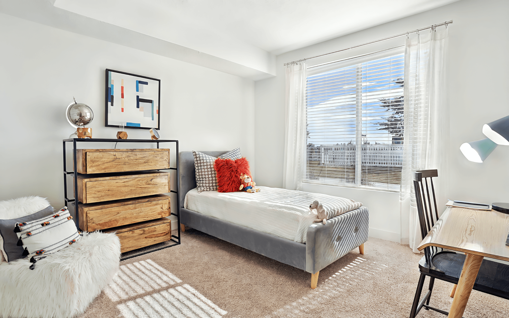 A bedroom with a bed, a dresser, and a chair.