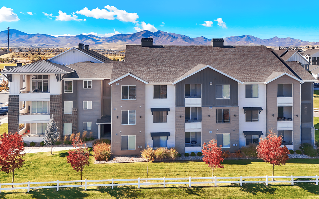 A large apartment complex with a white picket fence in front.