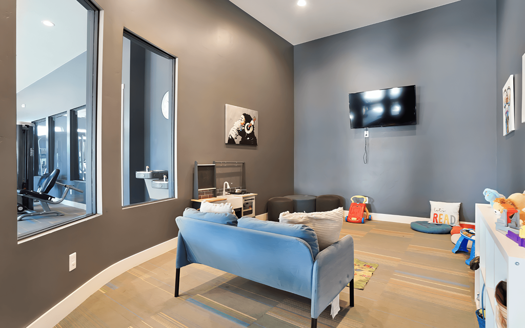 A bedroom with a blue bed and a television on the wall.