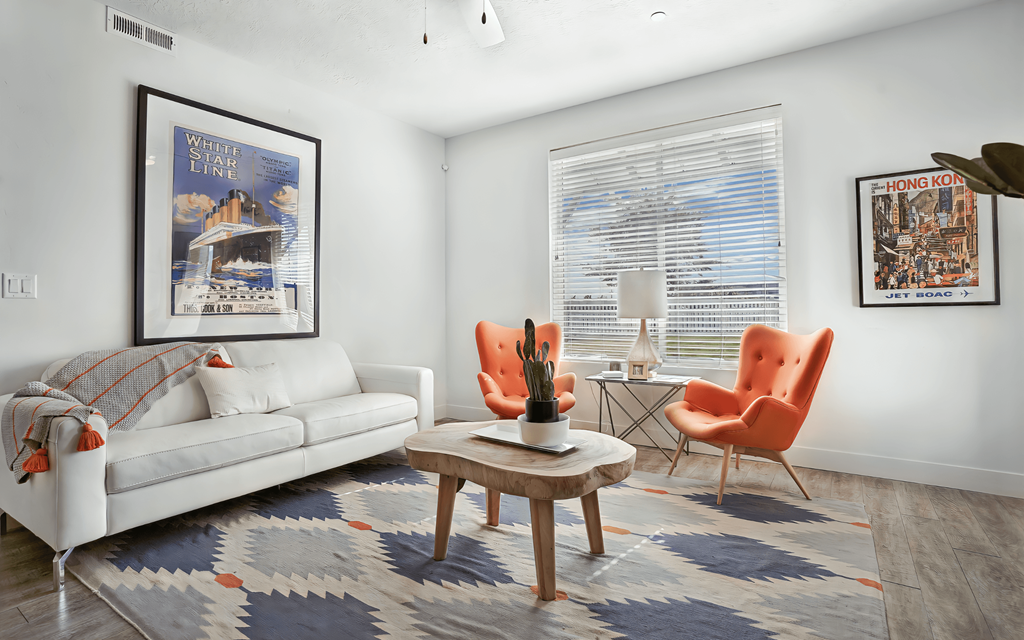 A living room with a white couch, a coffee table, and two chairs.