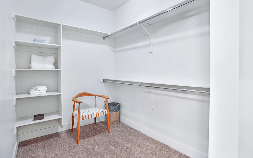 A room with a chair and a shelf with towels on it.