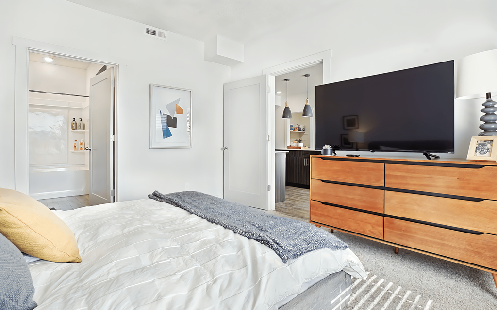 A bedroom with a bed, dresser, and a television.