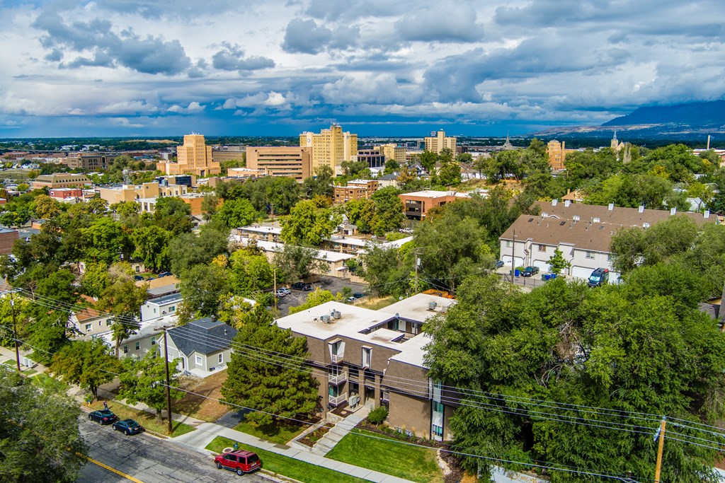 A cityscape with buildings and trees under a cloudy sky.