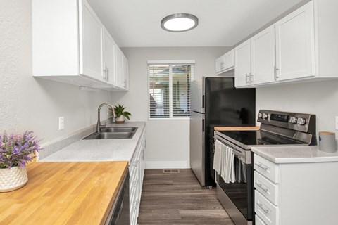 A kitchen with white cabinets and a black refrigerator.