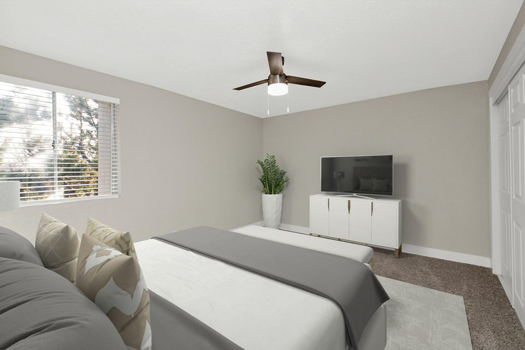 A bedroom with a bed, a television, and a plant.