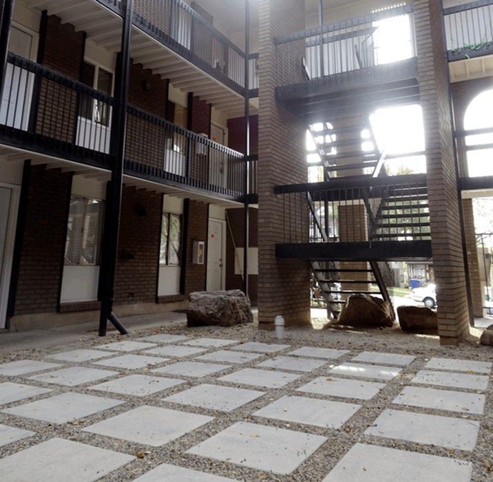 A large stone is on a tiled floor in front of a staircase.