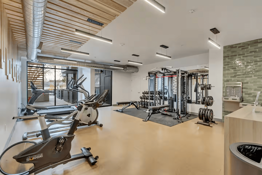 A gym with a variety of exercise equipment including treadmills, stationary bikes, and weight machines.