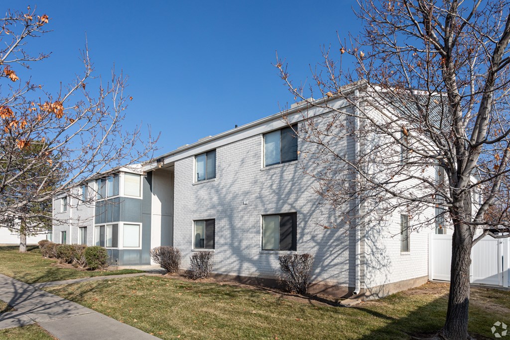 A modern building with a grey facade and a white fence in front.
