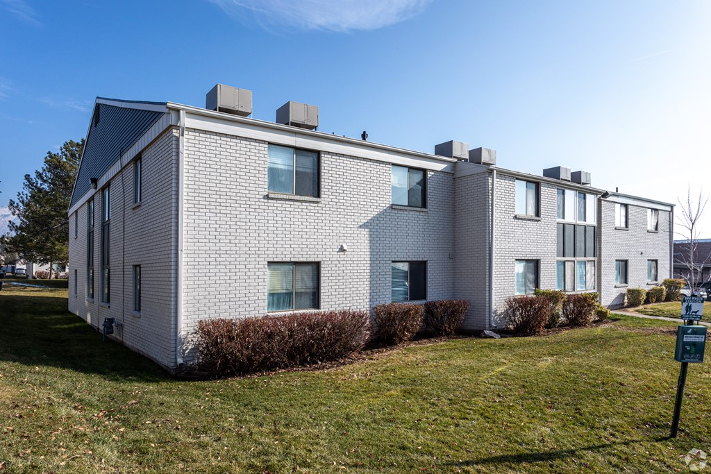 A white building with a black roof and a sign in front of it.