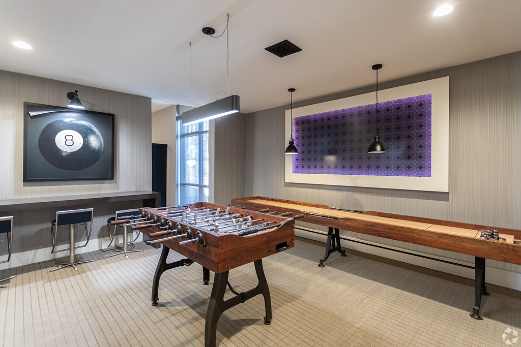 A room with a pool table and a purple wall hanging.