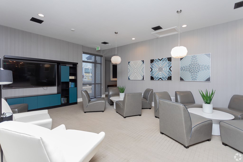 A modern waiting room with grey and white furniture and a television.