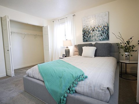 A bedroom with a bed covered in a blue blanket.