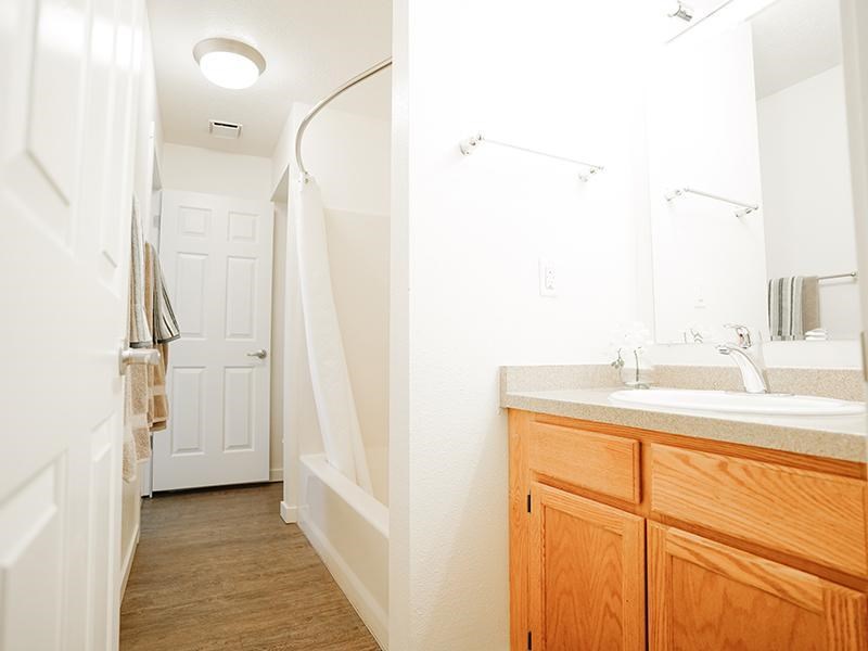 A bathroom with a wooden vanity and a white sink.