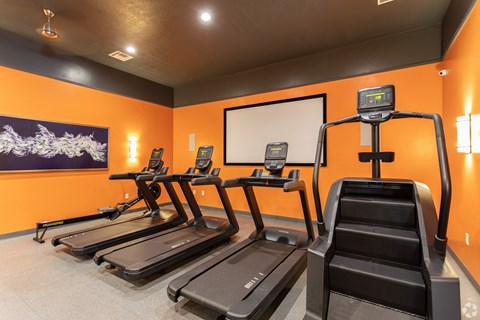 A gym with treadmills and a digital display.