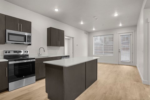 A modern kitchen with dark brown cabinets and stainless steel appliances.