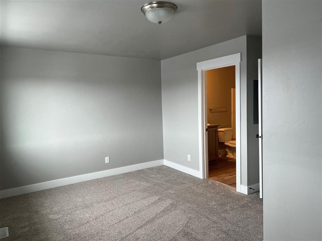 an empty room with a carpeted floor and a door to a bathroom