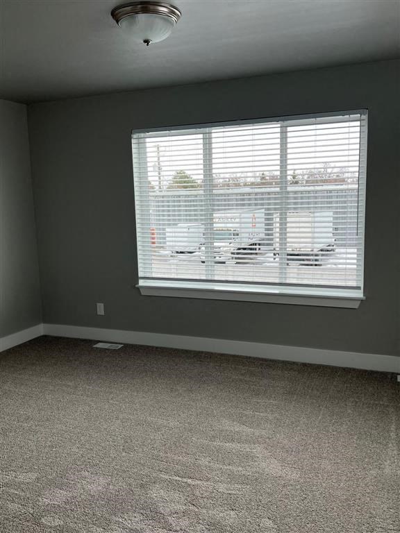 a living room with a large window and carpet