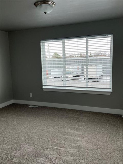 a living room with a large window and carpet