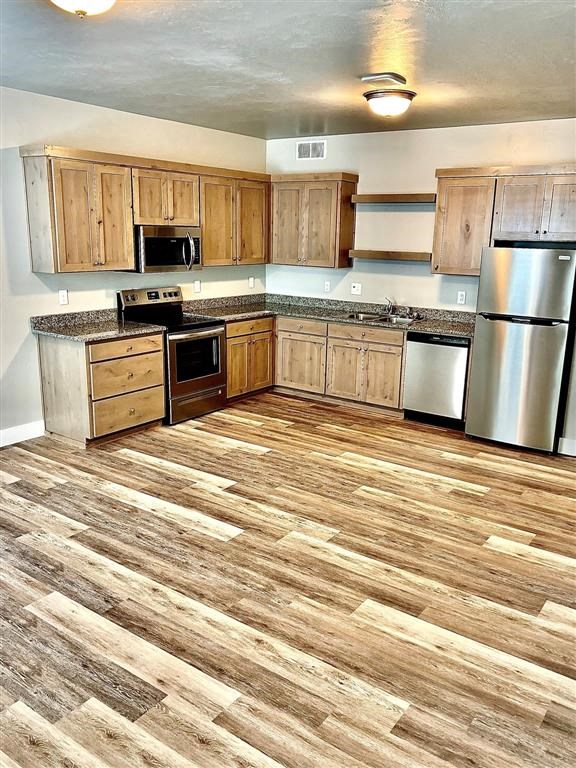 a kitchen with wooden floors and stainless steel appliances