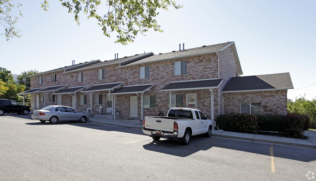 A white pickup truck is parked in front of a stone building.