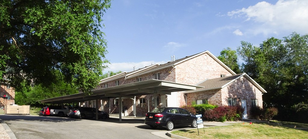 A car is parked in front of a building with a covered walkway.