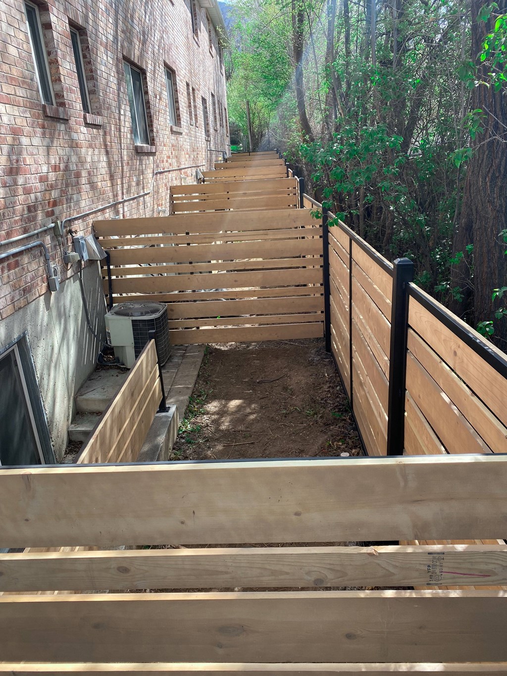 A wooden staircase with a black railing leads up to a building.