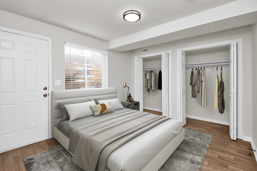 A bedroom with a bed, pillows, and a coat rack.