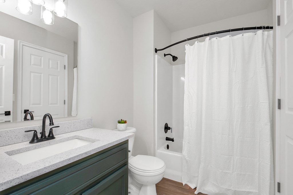 A white bathroom with a sink, toilet, and shower.