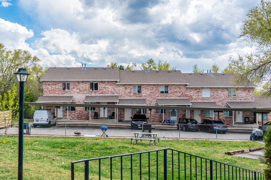 A large house with a stone facade and a black metal fence in front.
