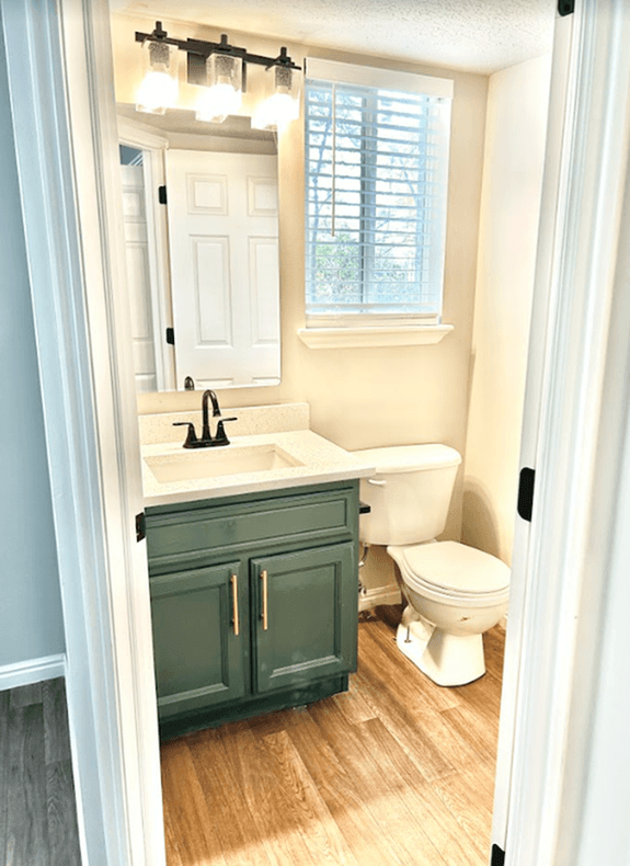 A bathroom with a green cabinet and a white toilet.