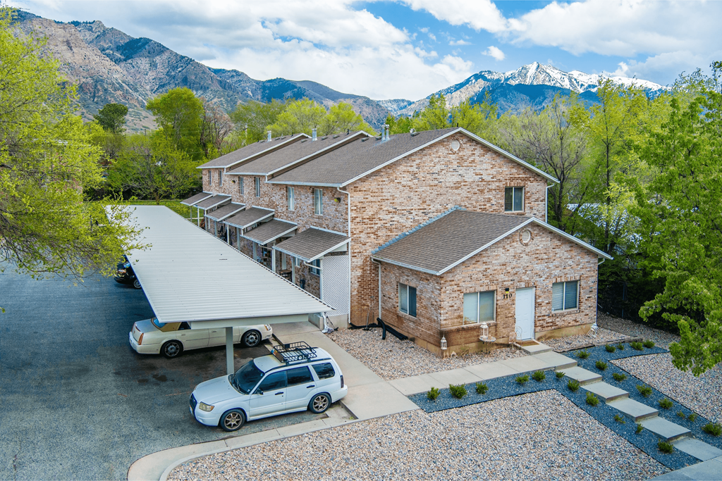 A house with a car parked in front and mountains in the background.