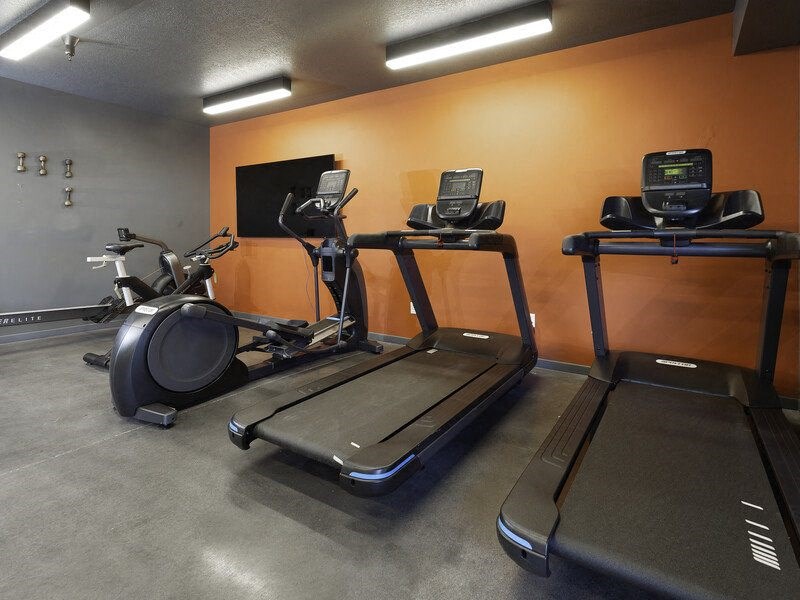 a gym with three treadmills and a tv