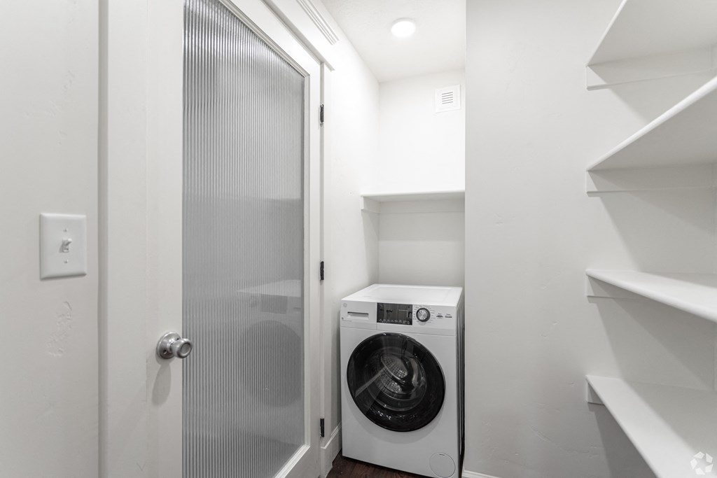 a small laundry room with a washing machine and a glass door