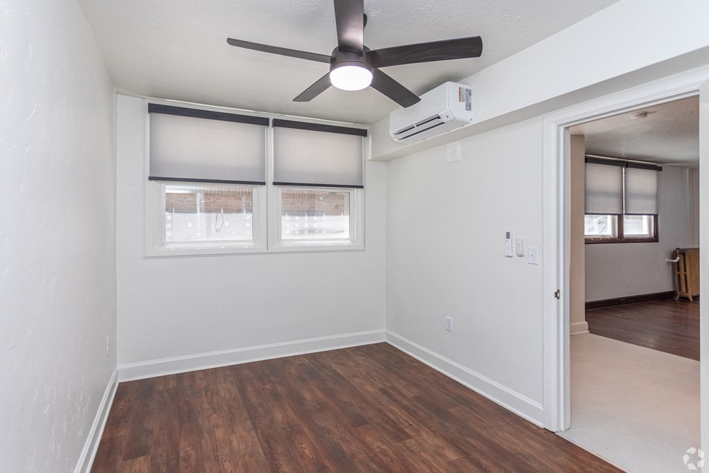 an empty living room with a ceiling fan and windows