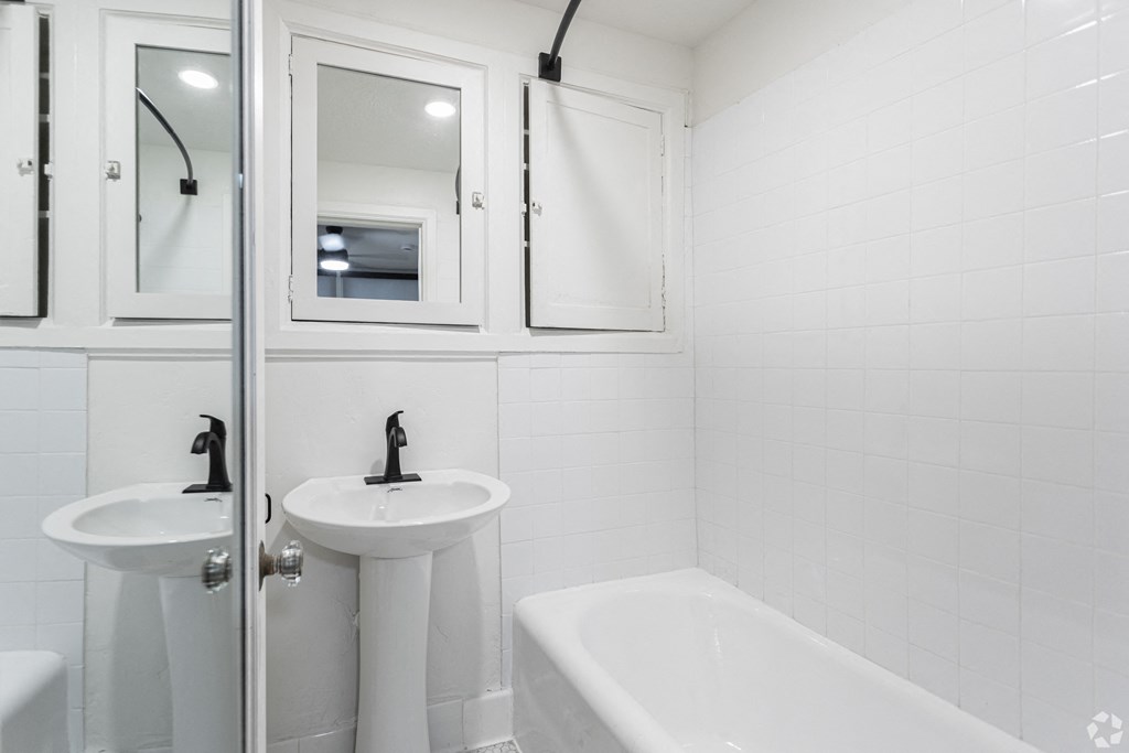 a white bathroom with two sinks and a tub and a shower
