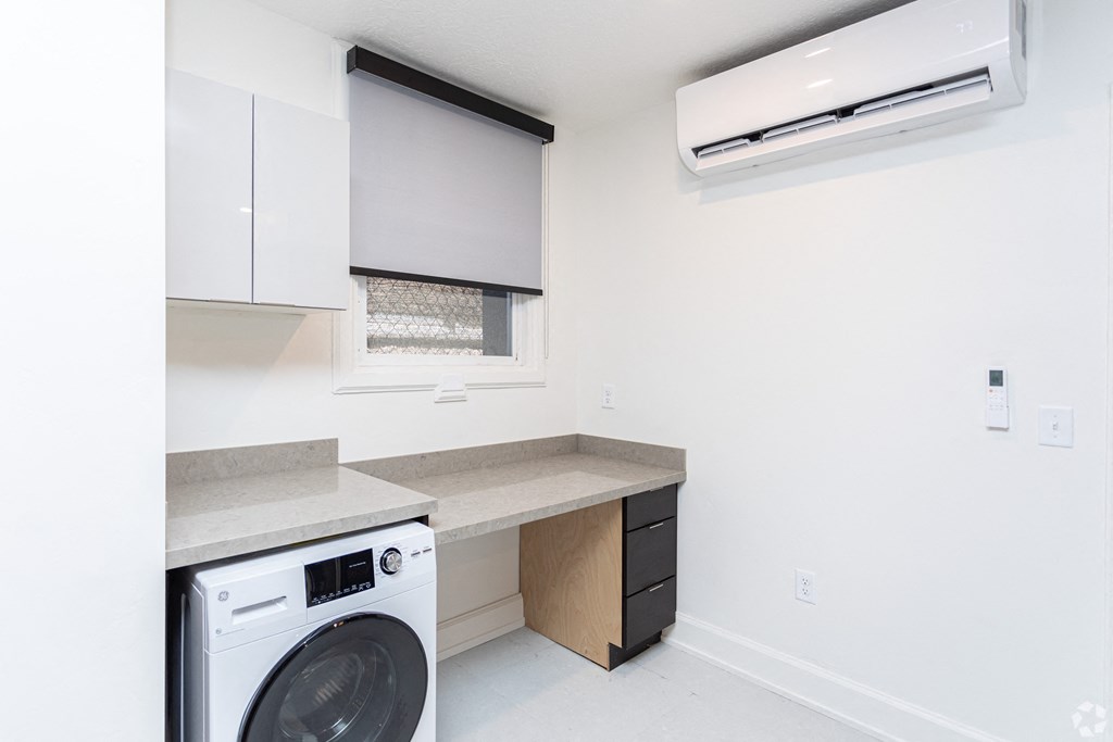 a white laundry room with a washing machine and a window
