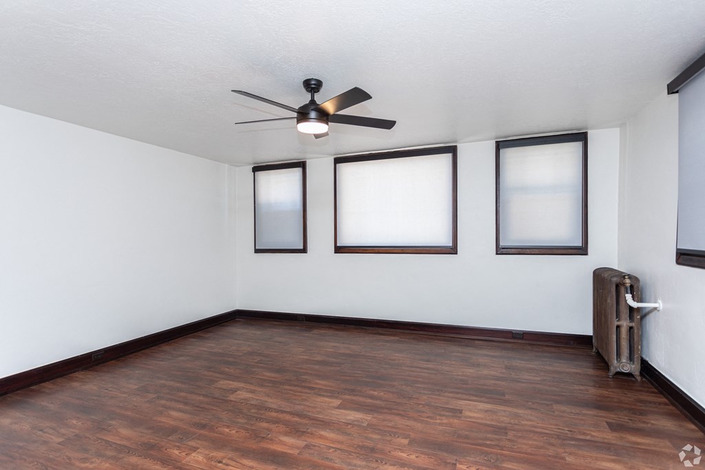 an empty living room with wood floors and a ceiling fan