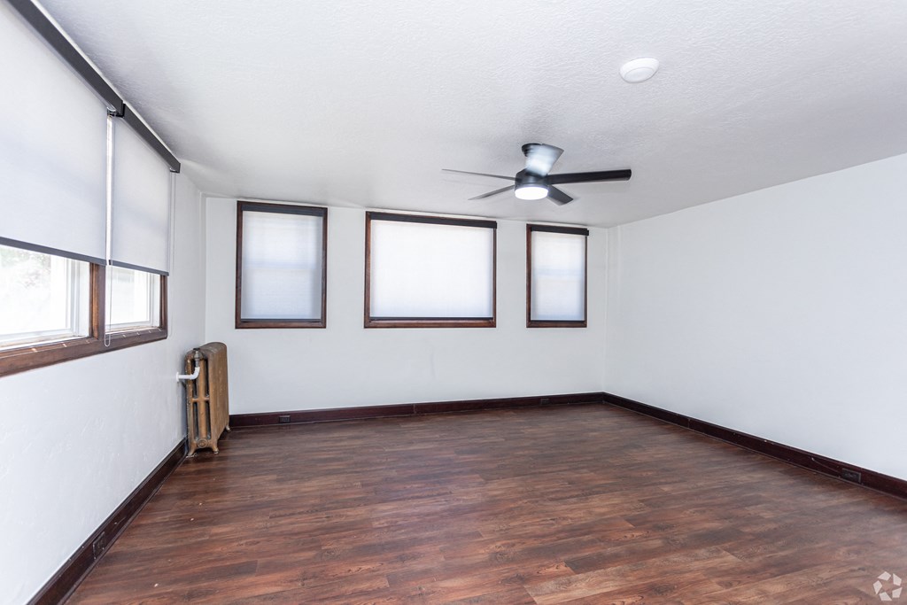 an empty living room with wood floors and a ceiling fan