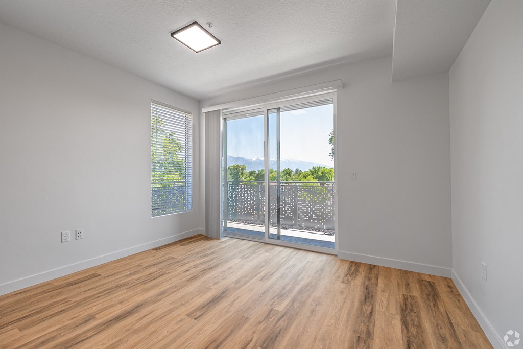an empty living room with a sliding glass door to a balcony at Lotus Gallacher luxury apartments for rent in Salt Lake City, UT