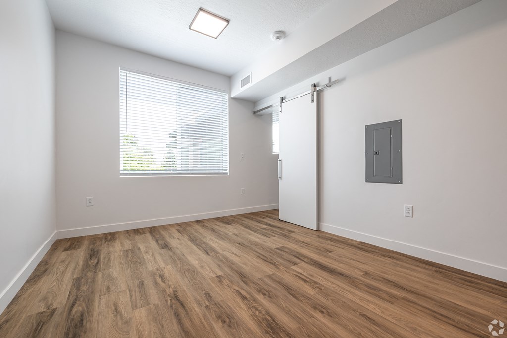an empty living room with a window and wood flooring at Lotus Gallacher luxury apartments for rent in Salt Lake City, UT